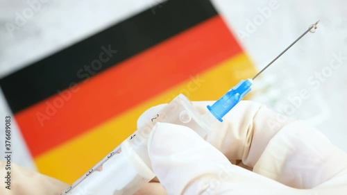 syringe with a vaccine is held by hand in a glove on background of the Germany flag, vaccine against coronavirus, Operation Warp Speed photo