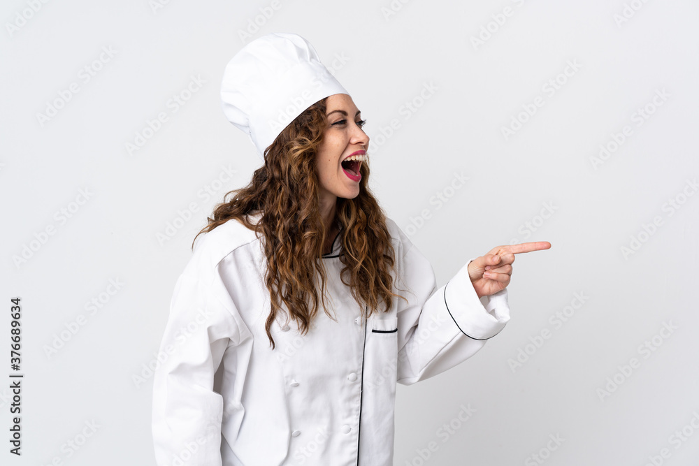 Young chef woman isolated on white background pointing finger to the side and presenting a product Young chef woman isolated on white background pointing finger to the side and presenting a product