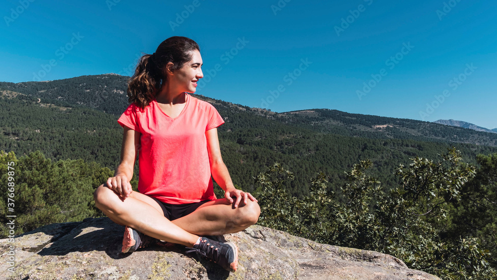 Young woman sitting on top of a rock