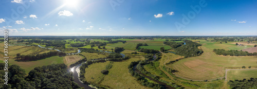 Super wide aerial panorama of the river Regge meandering through the green Dutch Twente farmland landscape against a blue sky and clouds photo