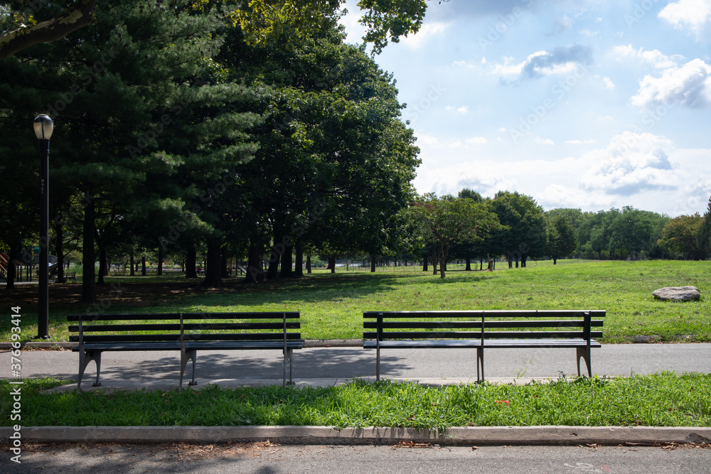 Empty Wood Benches and a Green Grass Field at Flushing Meadows Corona Park in Queens of New York City during Summer