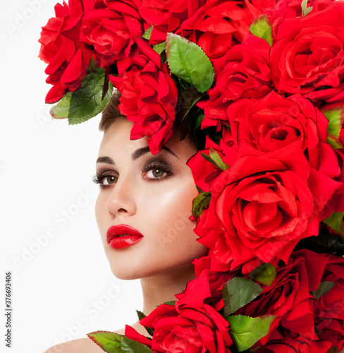 Beautiful woman face surrounded by red roses. Perfect skin. Professional makeup.
