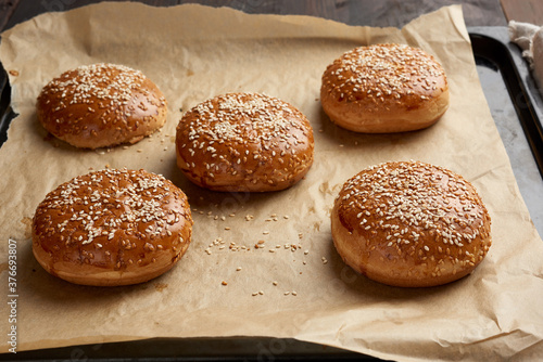 baked sesame buns on brown parchment paper, ingredient for a hamburger © nndanko