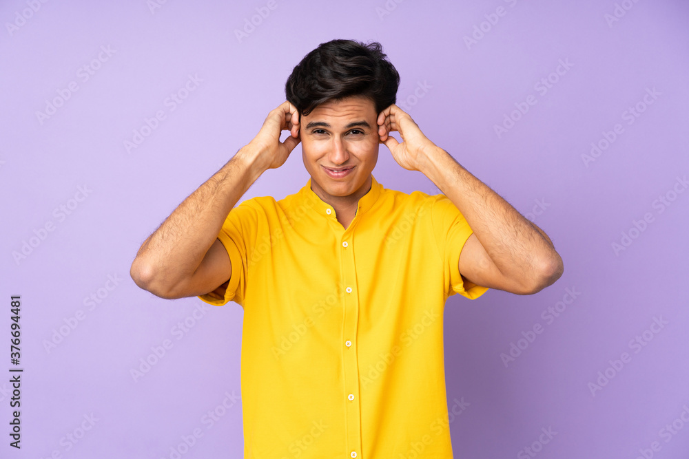 Man over isolated purple background frustrated and covering ears Man over isolated purple background frustrated and covering ears