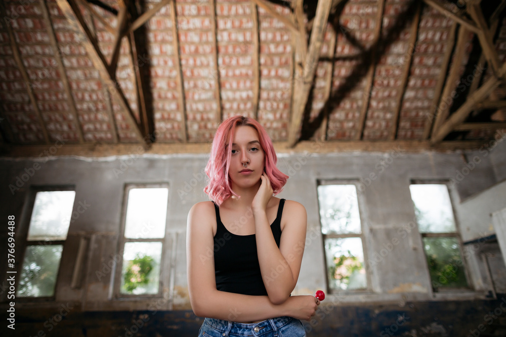 Young funky teenage girl with pink hair holding lollipop candy in abandoned building. Young funky teenage girl with pink hair holding lollipop candy in abandoned building.