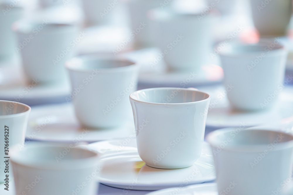 Many rows of white ceramic coffee or tea cups and saucers. Many rows of white ceramic coffee or tea cups and saucers.