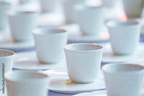 Many rows of white ceramic coffee or tea cups and saucers. © shine