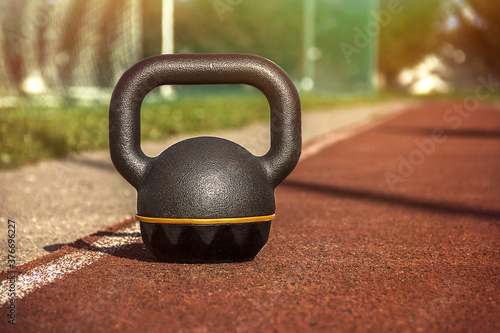 Kettlebell standing on rubber coating surface of outdoor workout ground photo