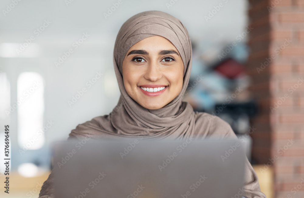 Portrait of pretty muslim girl in hijab using laptop Portrait of pretty muslim girl in hijab using laptop