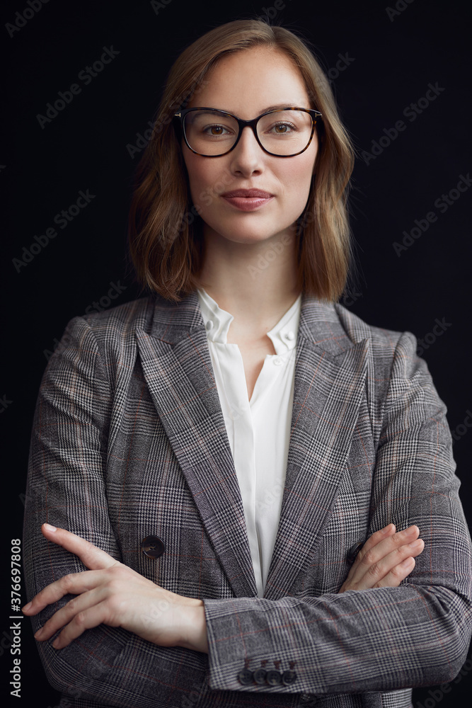 Portrait of young confident business woman, looking in to the camera, on a black background Portrait of young confident business woman, looking in to the camera, on a black background