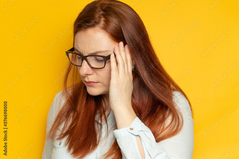 Worker young woman in glasses vision and with headache on yellow wall background. Stress, fatigue people concept. Hands hold their head, trying to find a solution to their problem