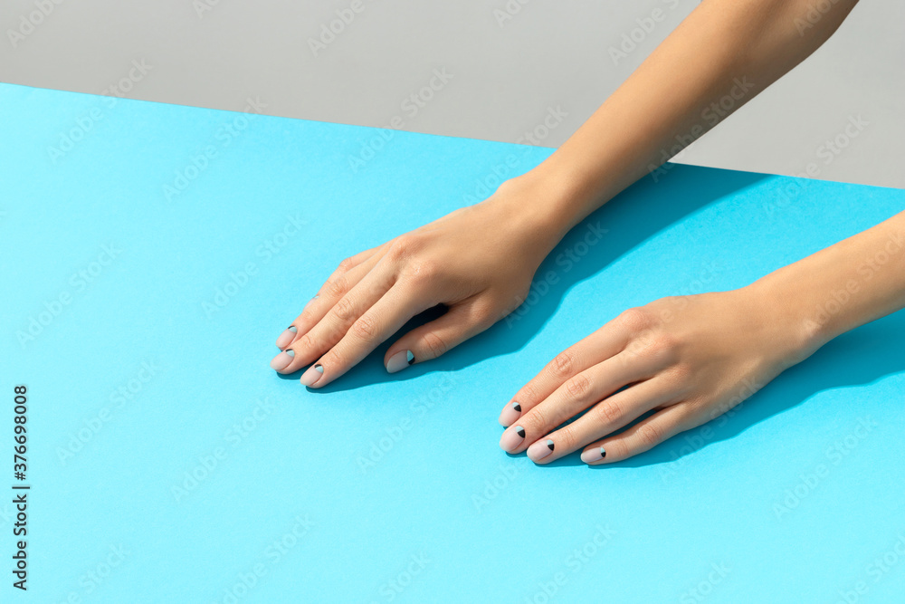 Womans hands with nude nail design over blue background Womans hands with nude nail design over blue background