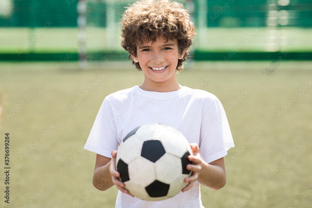 Boy holding soccer ball on the field