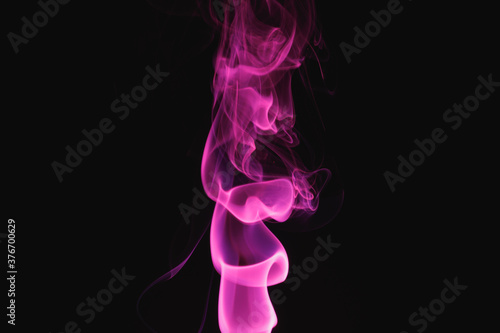 Purple smoke on a black background. Colored smoke. Incense stick smoke illuminated by purple light.