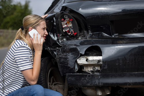 Unhappy Female Driver With Damaged Car After Accident Calling Insurance Company On Mobile Phone © Daisy Daisy
