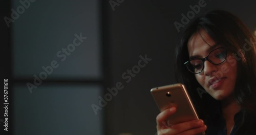 Young woman smiling while having a chat with her friends on whatsapp	