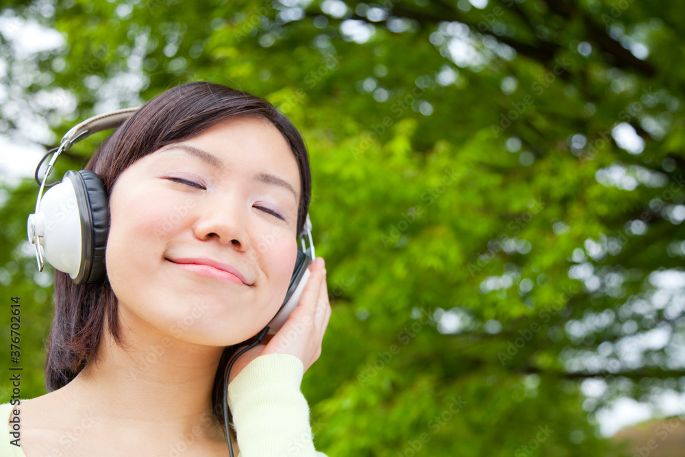 ヘッドフォンをつけて目を閉じる大学生 ヘッドフォンをつけて目を閉じる大学生