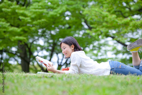 芝生に寝そべり読書する女性