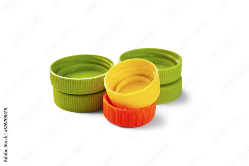 Close-up of recycled plastic bottle caps. Colored PET caps on a white background. Separate garbage collection. Recycling of plastic for prosthetics. Close-up of recycled plastic bottle caps. Colored PET caps on a white background. Separate garbage collection. Recycling of plastic for prosthetics.