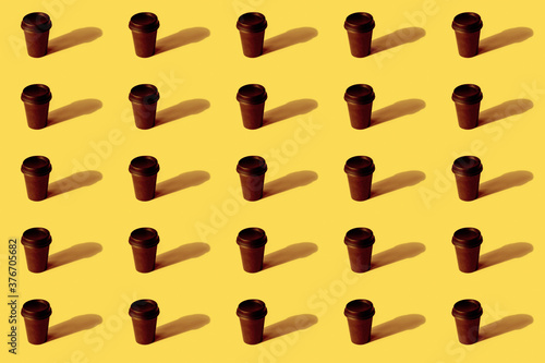Pattern of disposable coffee cup on yellow background, sharp shadows.