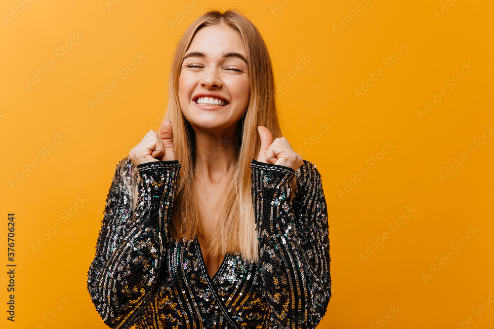 Wonderful cheerful girl enjoying photoshoot on orange background. Graceful fair-haired woman laughing with eyes closed. Wonderful cheerful girl enjoying photoshoot on orange background. Graceful fair-haired woman laughing with eyes closed.