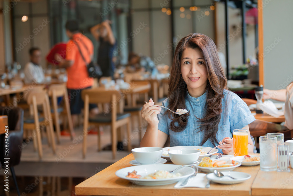 Asian woman ready to eating Boiled rice with pork and western food on table.