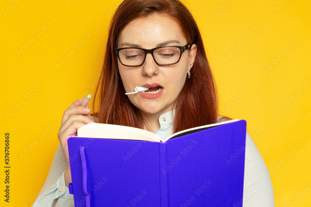 Portrait of concentrated teacher woman with notepad and pen in hands on a yellow background Portrait of concentrated teacher woman with notepad and pen in hands on a yellow background
