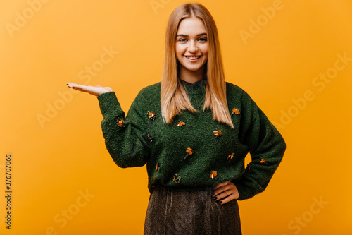 Pretty white girl with straight hairstyle laughing on yellow background. Wonderful european female model in green sweater enjoying photoshoot. photo