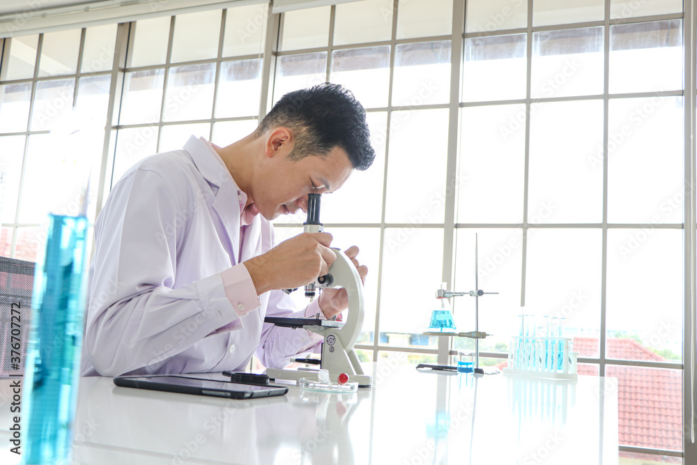 Asian scientists or chemists use a microscope. Asian scientists or chemists use a microscope.