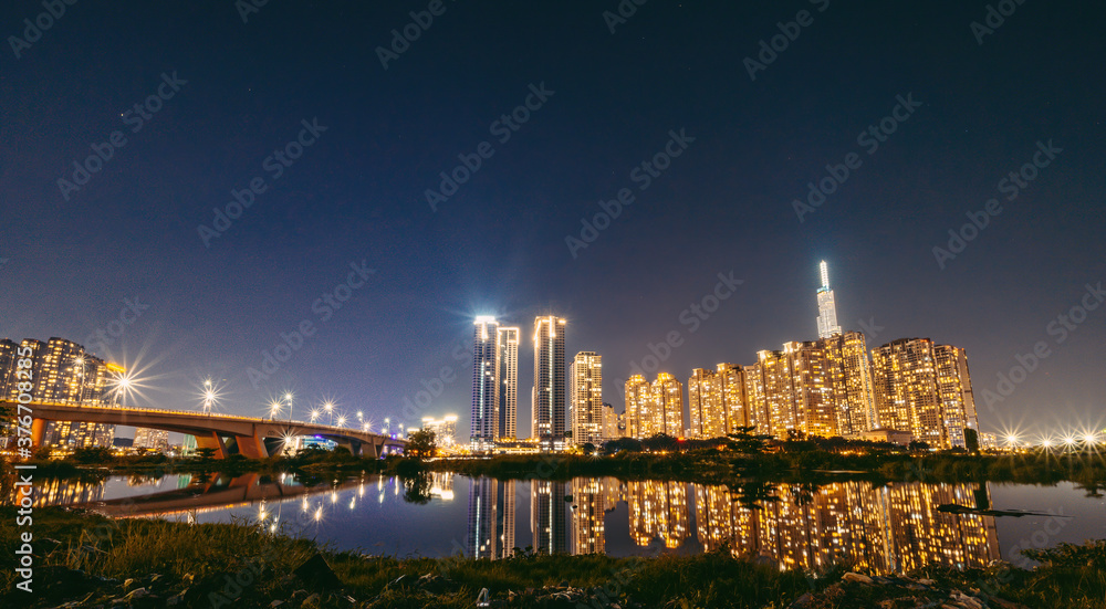 Panorama night view at Landmark 81 is a super tall skyscraper in center Ho Chi Minh City, Vietnam and Thu Thiem bridge with development buildings.