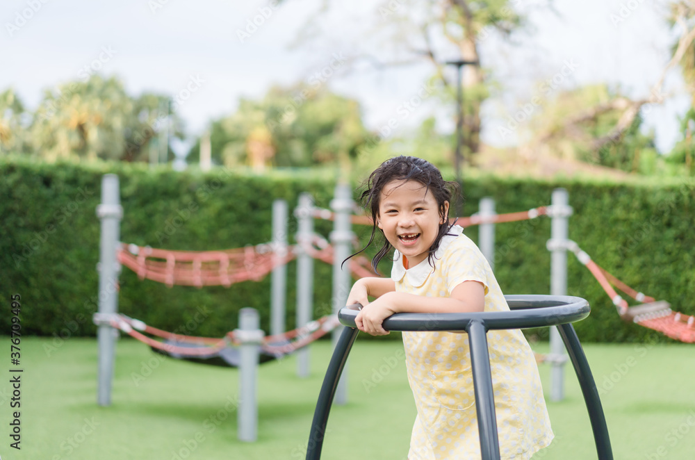 Obraz premium Asian kid girl playing on a swing and having fun in park.Little asian girl climbing rope at playground.Asian child girl playing on playground in outdoor park.Happy Little asian girl outdoor play park.