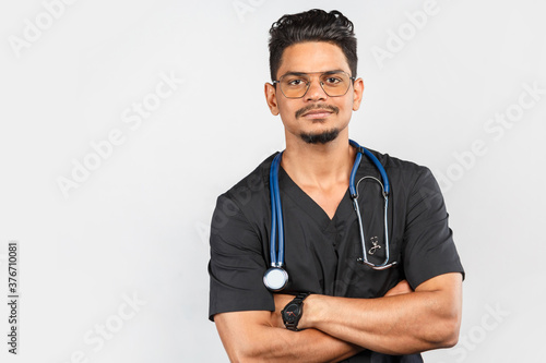 Indian / Asian doctor with stethoscope in uniform on gray background.