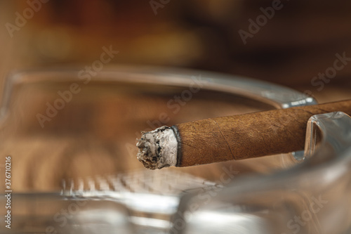 Lighted cigar in an ashtray close up