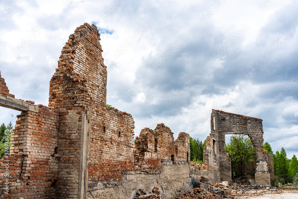 Destroyed wall. Fragments of the wall against the sky. Ruins of houses. Summer day.
