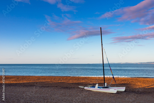 Small catamaran sail boat on an empty beach