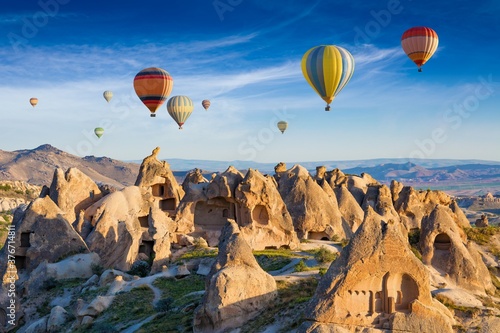 Colorful hot air balloons fly in blue sky over amazing rocky valley in Cappadocia, Turkey. photo