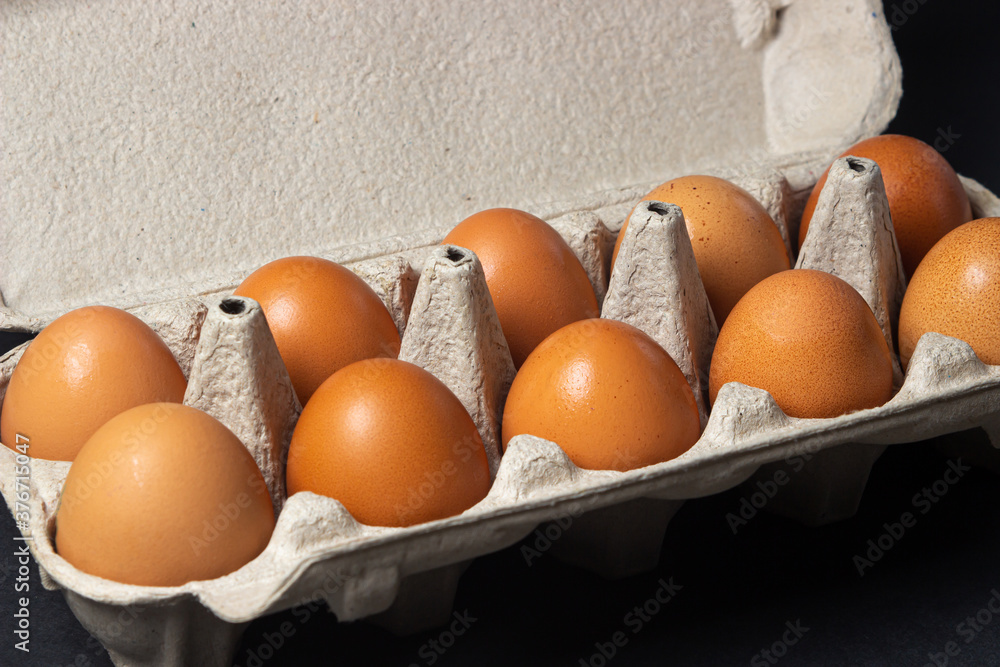 Eggs on a black background. Chicken eggs in a paper box Eggs on a black background. Chicken eggs in a paper box