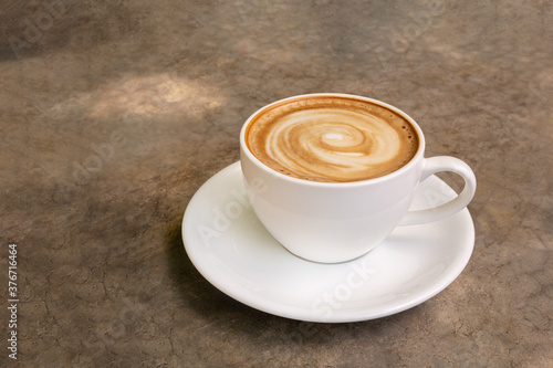 Hot coffee cappuccino latte art spiral shape in ceramic cup on concrete table background
