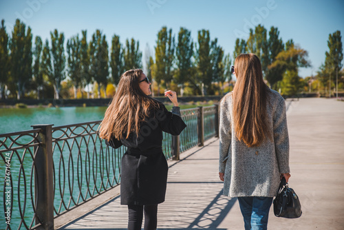 two girlfriends walking by city quay in coats autumn fashion photo