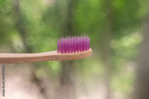 bamboo toothbrushes close-up on nature background. green bokeh. biodegradable materials. Eco-friendly plastic replacement. pink bristles