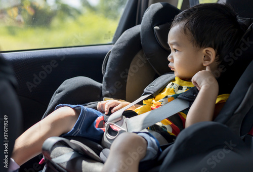 Adorable Asian kid boy (Toddler age 1-year-old) Protection Sitting in the Car Seat with Safety Belt Locked.