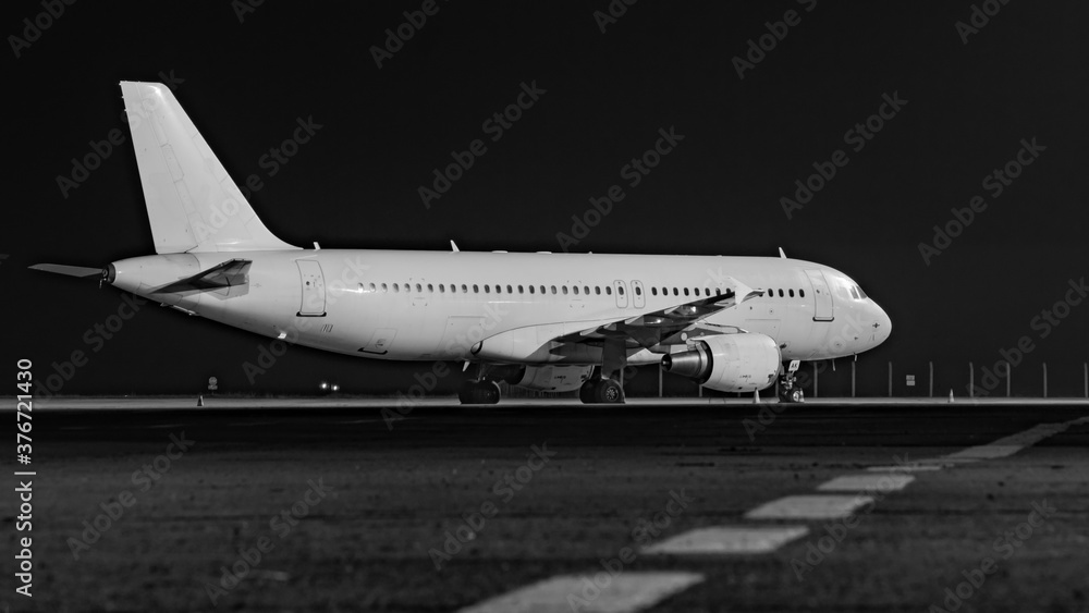 Side view of white airplane on dark night sky background. Jet commercial aircraft on airport apron, low night light. Modern technology in fast transportation, private business travel, charter flight.