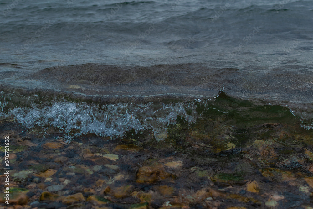 dark bright green waves of lake baikal, in overcast summer, stones in water, coast dark bright green waves of lake baikal, in overcast summer, stones in water, coast