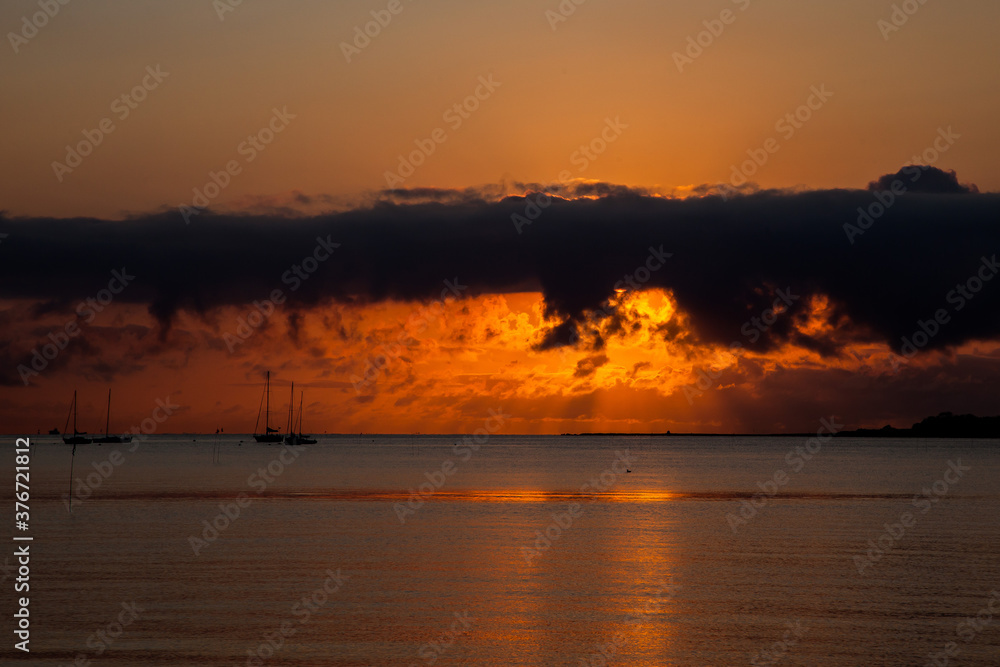 Beautiful sunrise on beach with boats in distance with clodscape