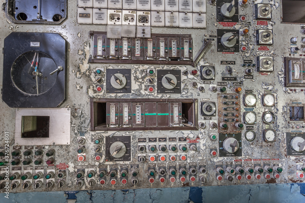 Several gauges, switches and buttons on a control panel left forgotten in an abandoned factory in the deep south