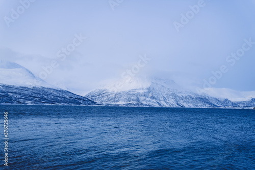 Scenic view of scandinavian fjords lands on northern environment and calm lake water surface, beautiful tranquil view of national park destination landscape in winter