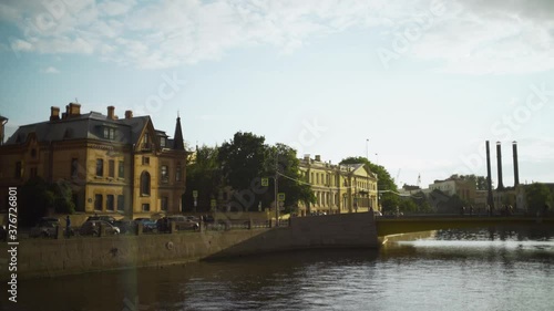 Beautiful old architecture in brick modernist style. Acion. Historical brick building located on city river with walking people. Architect Schroeter's house on Moika embankment photo