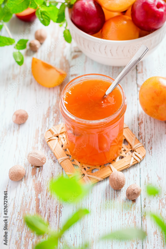 Yellow and red plums in a plate and jar of plum jam on worn wooden table flat lay, autumn fruit preserves concept, copy space Yellow and red plums in a plate and jar of plum jam on worn wooden table flat lay, autumn fruit preserves concept, copy space