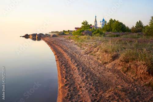 The shore of lake Peipus at sunset. Church of the apostles Peter and Paul in Vetvenik, Pskov region. photo