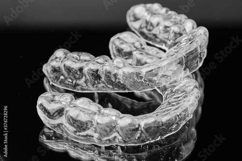 Invisible transparent dental removable braces on the black background. Orthodontic appliance for dental correction. Aligners for teeth straightening.